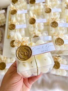 a person holding up a small package with wedding favors in front of other packages on the table