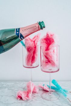 two wine glasses filled with pink and blue yarn next to a bottle of chandon