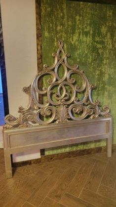 a metal bed frame sitting on top of a wooden floor next to a green wall