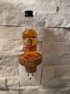 a bottle of whiskey sitting on top of a light switch box in front of a brick wall