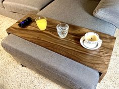 a wooden tray with two glasses and a bottle on it sitting on the floor next to a couch