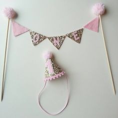 pink and silver party hats with pom poms hanging from the top on a white background