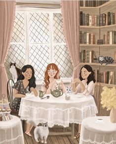 three women sitting at a table with cats