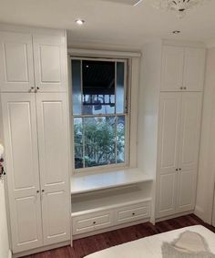 a bedroom with white cabinets and a window