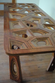 a wooden table with intricate carvings on the top and sides, sitting on a hard wood floor