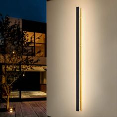 a modern light fixture on the side of a building in front of a house at night