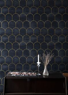 a table with vases and flowers on it in front of a wallpapered background