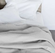 an unmade bed with white sheets and pillows