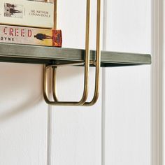 a book shelf with two books on top of it and a pair of scissors hanging from the wall