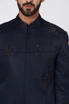 a man wearing a dark blue jacket with embroidered flowers on it