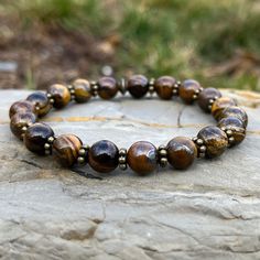 Handmade Genuine Stone Bracelets High-Quality Beaded Bracelet Genuine 8mm Tiger Eye Stone Beads Stretch Bracelet Made With Quality Cord & Antique Bronze Spacers Made With Pure Positive Energy Tiger Eye Properties - Will & Courage - Luck & Success - Prosperity - Grounding & Physical Vitality These Quality Bracelets Will Add A Touch Of Casual Elegance To Your Wardrobe For Any Season Of The Year. All Bracelets Come Carefully Packaged In A Gift Box Ready For Giving. Adjustable Polished Beads Bracelets For Meditation, Adjustable Brown Polished Bead Bracelets, Adjustable Brown Polished Beads Bracelet, Brown Bracelets With Spacer Beads For Jewelry Making, Brown Bracelets With Spacer Beads For Gifts, Adjustable Faceted Beads Bracelet For Meditation, Adjustable Spiritual Bracelet With Polished Beads, Spiritual Brown Beaded Bracelets With Faceted Beads, Brown Bracelets With Spacer Beads As Gift