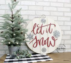 a wooden sign that says let it snow next to a small christmas tree