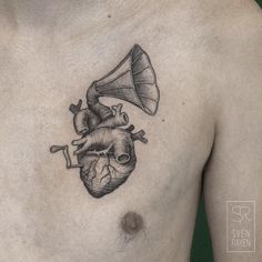 a man with a tattoo on his chest has a musical instrument in the shape of a heart