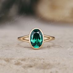 a close up of a ring with a green stone in the center on a rock