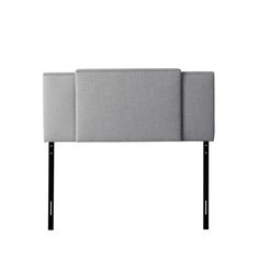 an upholstered headboard with black legs and a light gray fabric cover on it