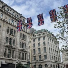 the british flag is flying in front of some old buildings with cars parked on the street