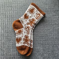 a brown and white knitted sock laying on top of a gray surface next to a coffee cup