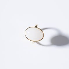 a white and gold ring sitting on top of a white surface with a shadow coming from it