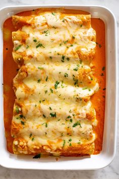 an enchilada in a white casserole dish on a marble surface