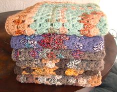 a stack of crocheted blankets sitting on top of a wooden table