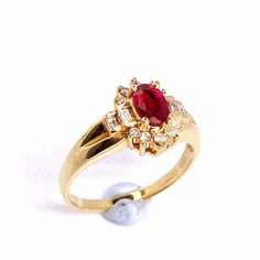 a gold ring with a red stone surrounded by white pearls