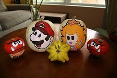 pumpkins decorated with mario and luigi's faces are sitting on a table in front of a couch