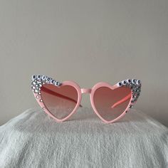 a pair of pink sunglasses with heart shaped frames and embellishments on the sides