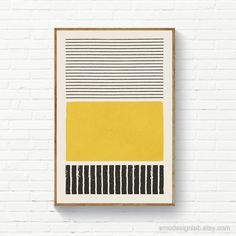 a yellow and black painting hanging on a white brick wall