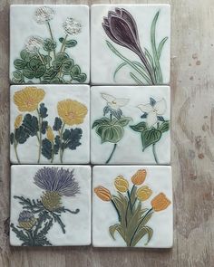 four square tiles with flowers painted on them