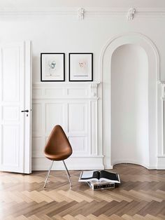 an open book on the floor next to a chair in a room with white walls