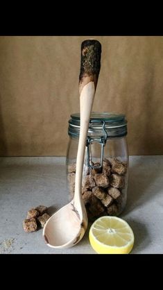 a wooden spoon sitting next to a glass jar filled with dog food and a lemon