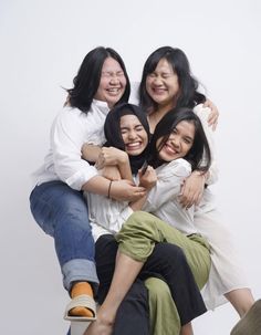 four women are sitting on top of each other posing for the camera with their arms around one another