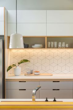 a kitchen with white cabinets and counter tops next to a refrigerator freezer filled with dishes