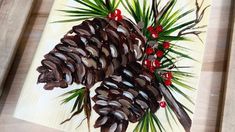 a pine cone with red berries and green leaves on a wood paneled table top