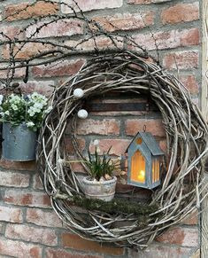 a wreath is hanging on the side of a brick wall next to potted plants