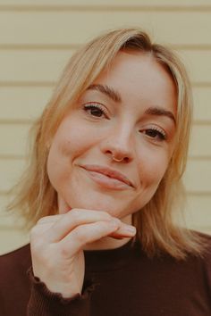 a close up of a person with a smile on their face and hand near her chin