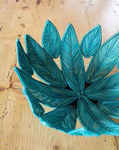 a blue vase sitting on top of a wooden floor next to a plant pot filled with leaves