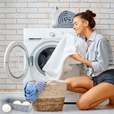 a woman sitting on the floor next to a washing machine