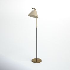 a floor lamp with a white shade on the top and a black base, standing in front of a white wall