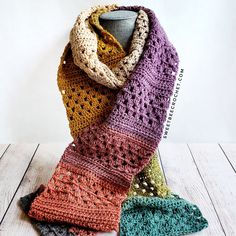 a multicolored crocheted scarf sitting on top of a wooden table