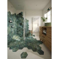 a bathroom with green tiles on the floor and walls, along with a wooden cabinet