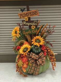 a pumpkin shaped arrangement with sunflowers and fall leaves in front of a garage door