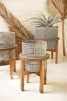 three metal planters sitting on top of wooden stands