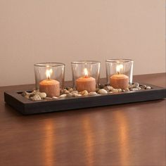 three candles are lit on a tray with rocks