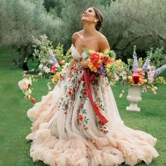 a woman standing in the grass with flowers on her dress