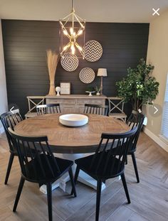 a dining room table with black chairs and a white bowl on the centerpiece in front of it