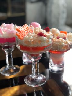 three desserts sitting on top of a table in small glass dishes with fruit and marshmallows