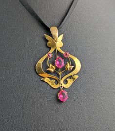 This antique, Art Nouveau era, 9ct gold and pink paste pendant really pops. It is a lavaliere style pendant, typically popular in the Edwardian / Art Nouveau era, they were usually light and delicate settings but with elaborate designs and skillful metalwork. This pendant has vibrant pink paste carefully set at intervals within the rich bloomed gold setting, it features a pretty floral design to the centre with a butterfly shaped finial just below the integral bale. A very pretty pendant and a nice unusual find in vibrant pink.  Marks and era: It is marked AB makers mark and 9ct for 9ct gold, Art Nouveau era, C1900s.  Condition: Good used condition overall, some light surface wear commensurate with age, minor surface wear to the stones. Approx measurements: 1.75" length  1.10" width  Weigh Antique Pink Brooch Jewelry, Antique Hallmarked Pink Jewelry, Antique Pink Hallmarked Jewelry, Pink Antique Hallmarked Jewelry, Pink Victorian Jewelry In 14k Gold, Edwardian Art, Gold And Pink, Pretty Pendant, Butterfly Shape