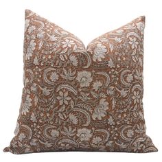 a brown and white pillow with an intricate design on the front, sitting on a white background