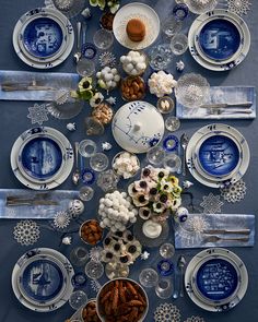 the table is set with blue and white plates, silverware, and other decorations